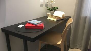 A desk with a computer, a chair, a potted plant, and books.