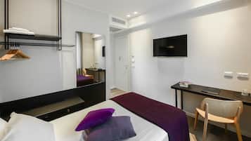Una habitación de hotel moderna con una cama, un escritorio, una silla, un televisor y un espejo.