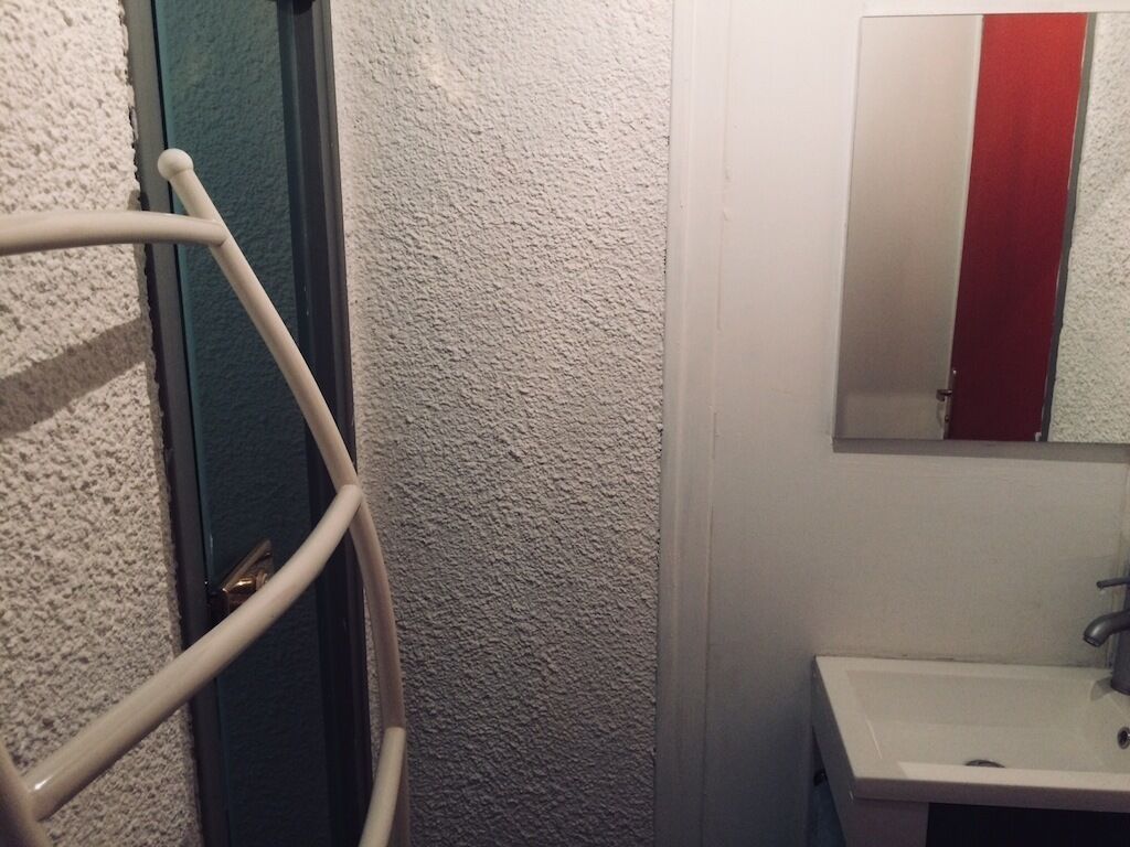 Une salle de bain avec un lavabo blanc, un miroir orné d’une bande rouge et un porte-serviettes.