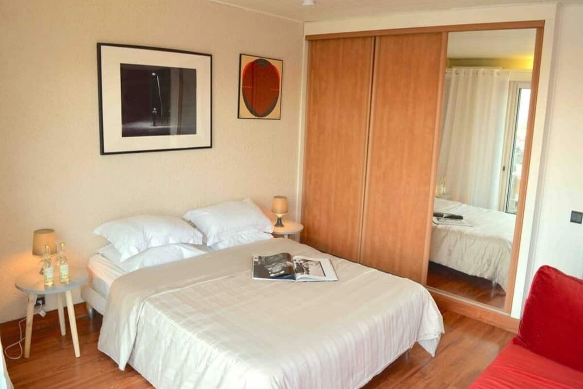 Une chambre à coucher avec un lit, des tables de chevet, un miroir et un canapé rouge.