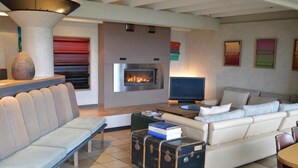 A modern living room with a fireplace, a sofa, a bench, and a coffee table. - Casa Marta : Suites - Terrasses et vue Panoramique (Tournon-sur-Rhone)