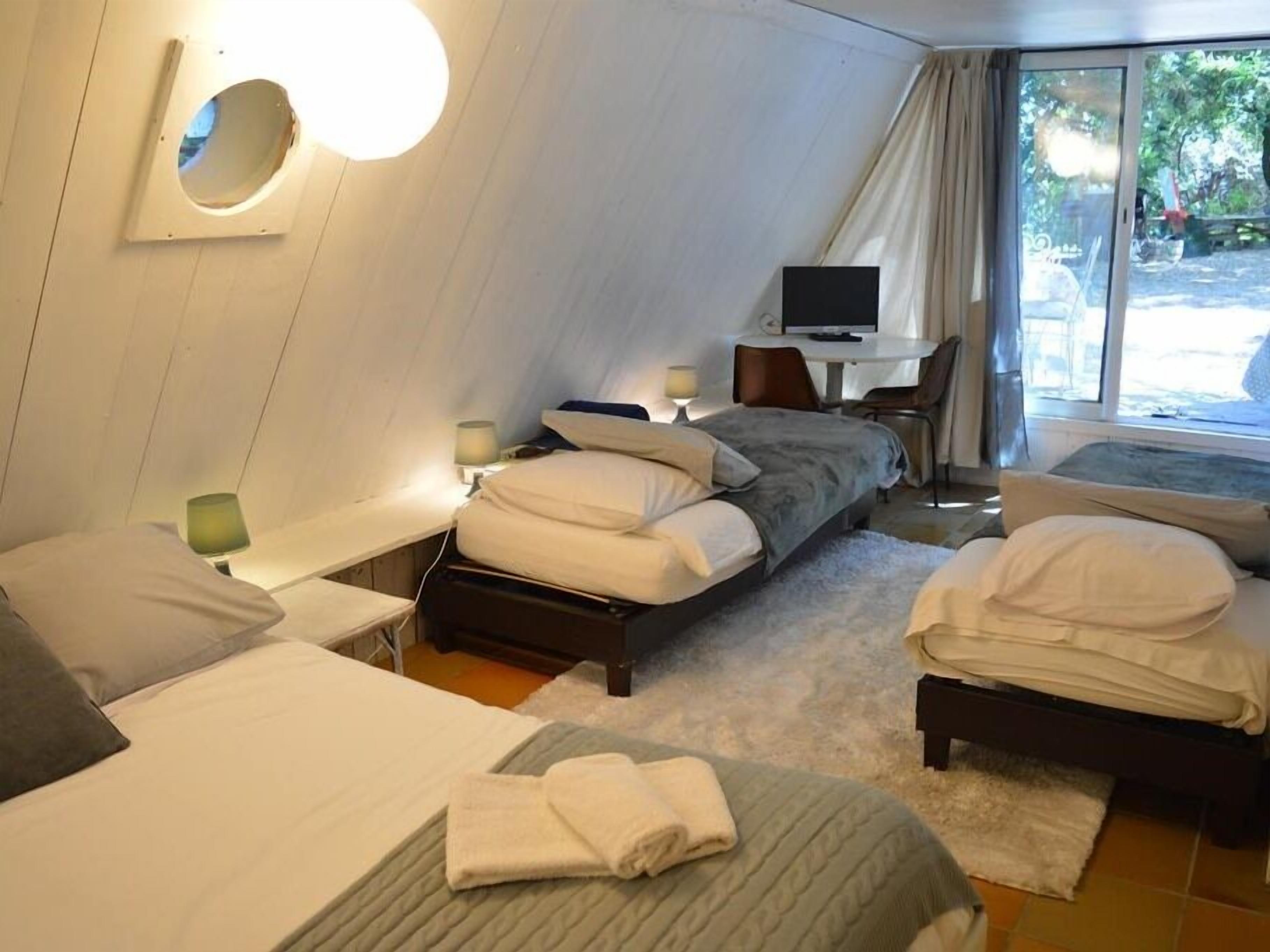 A hotel room with two beds, a television, and a window with curtains.