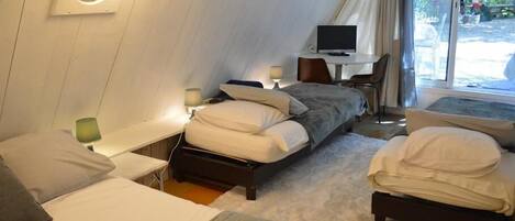 A hotel room with two beds, a television, and a window with curtains.