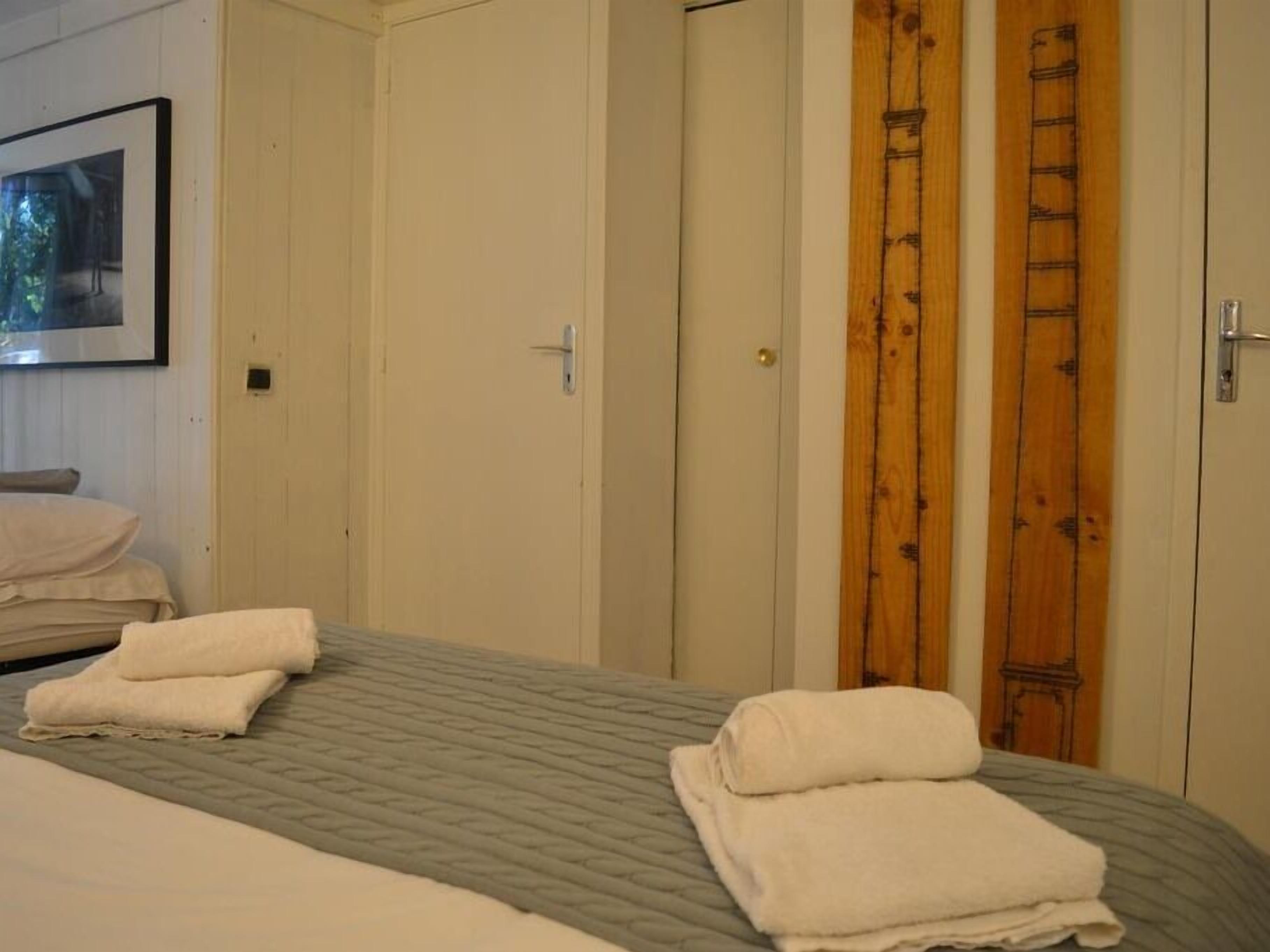 A bedroom with a bed, two doors, and a ladder leaning against one of the doors.