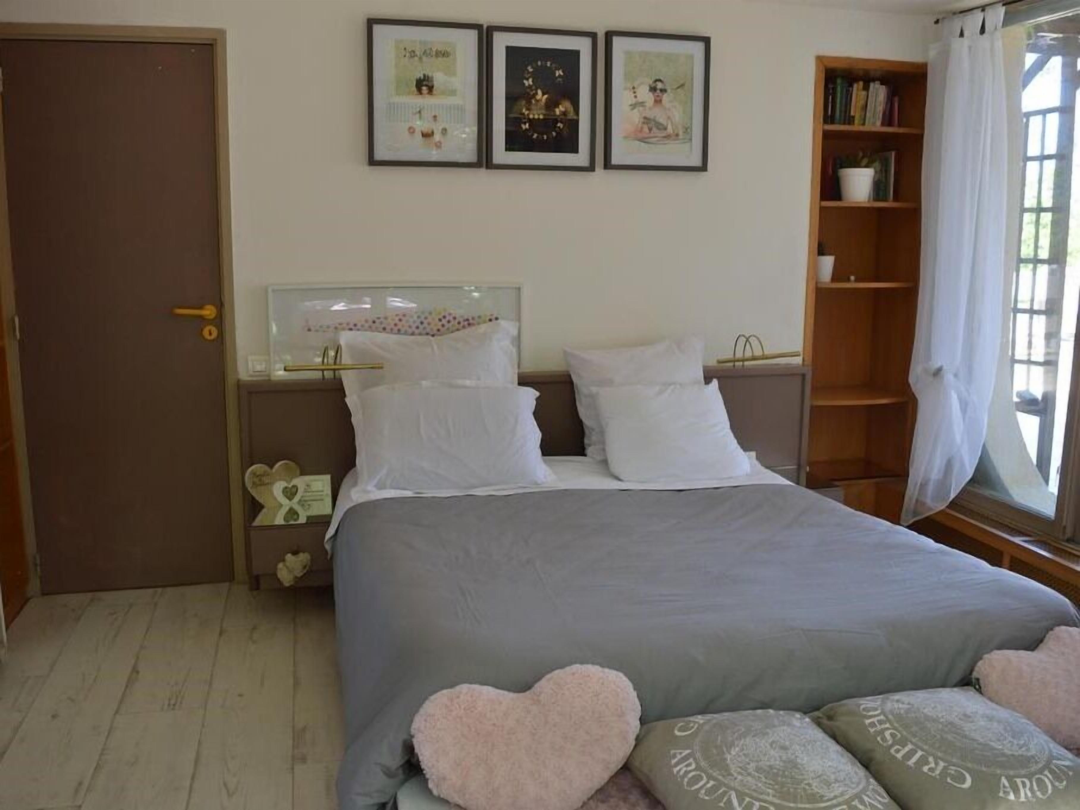 Un dormitorio con cama, mesitas de noche, una estantería y una puerta.