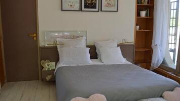 Un dormitorio con cama, mesitas de noche, una estantería y una puerta.