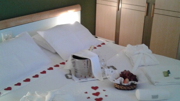 A neatly made bed with white linens, a small basket of fruit, and a bottle of water. - Apart Quartier Latin Hotel (Vitoria)
