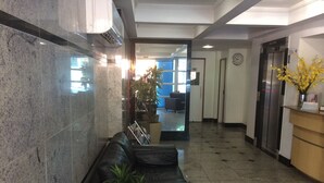 A lobby with a marble wall, a reception desk, a black leather sofa, and a potted plant. - Apart Quartier Latin Hotel (Vitoria)