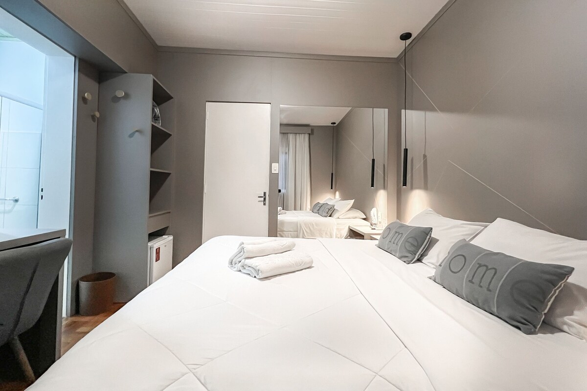A hotel room with a large bed, bedside tables, a wardrobe, and a mirror.