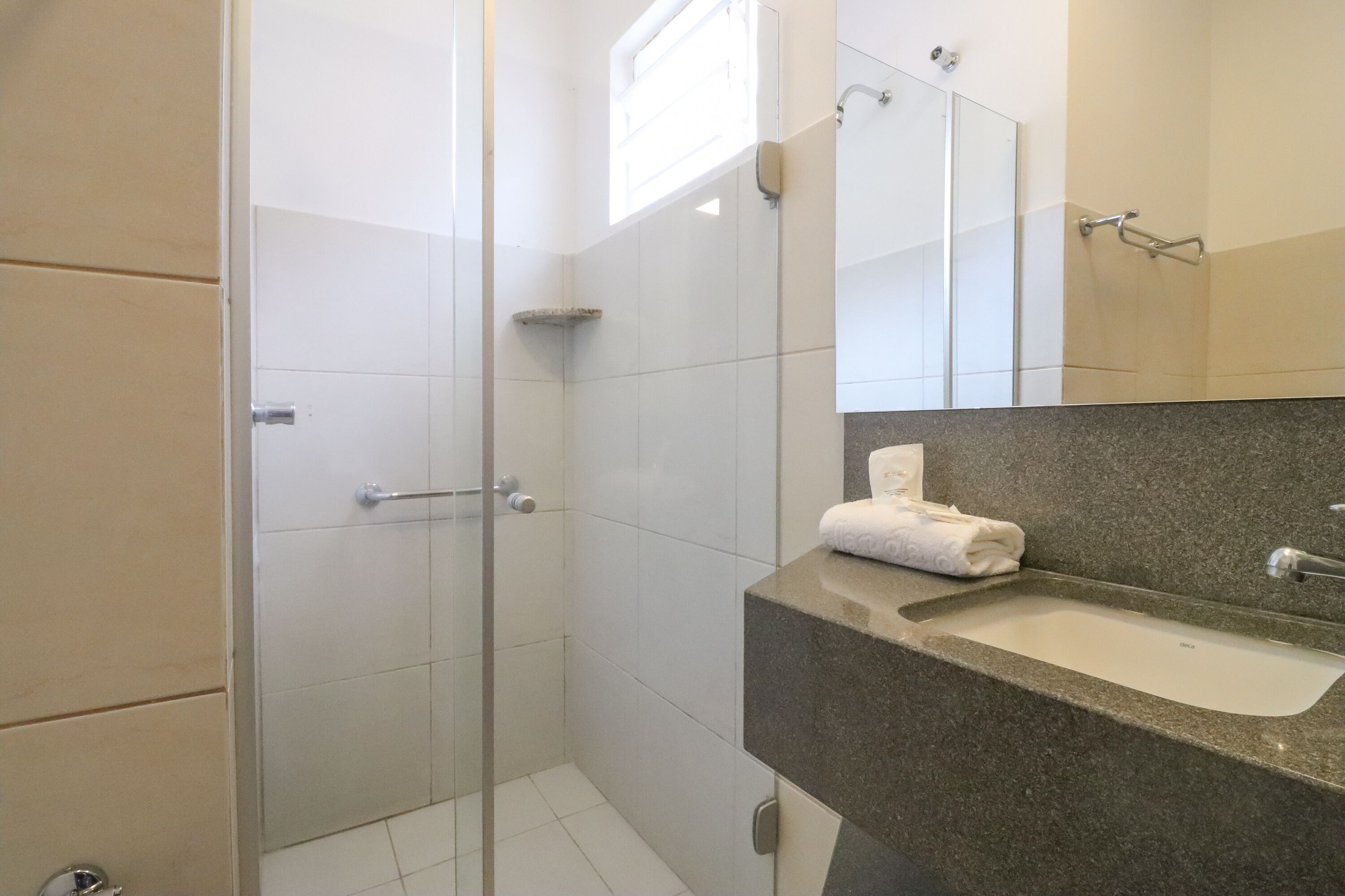 Un baño moderno con ducha de vidrio, lavamanos con encimera de granito y un espejo sobre el lavamanos.