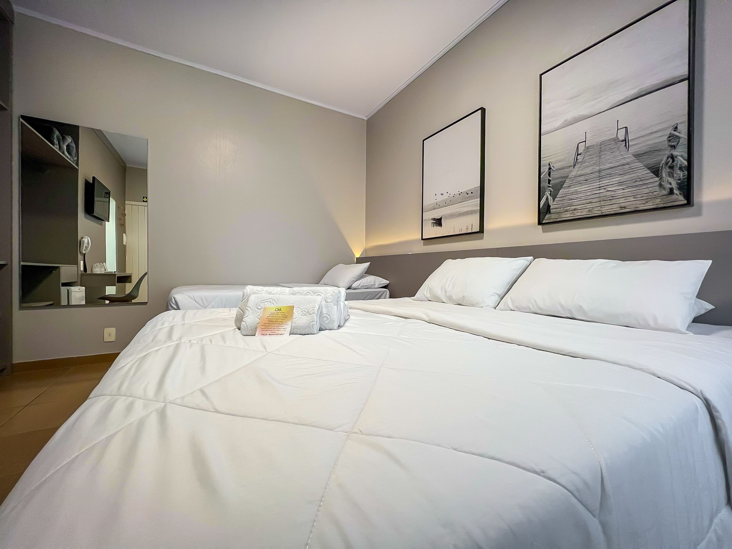 Ein Hotelzimmer mit einem großen Bett, einem Nachttisch, einem Spiegel und zwei gerahmten Bildern an der Wand.