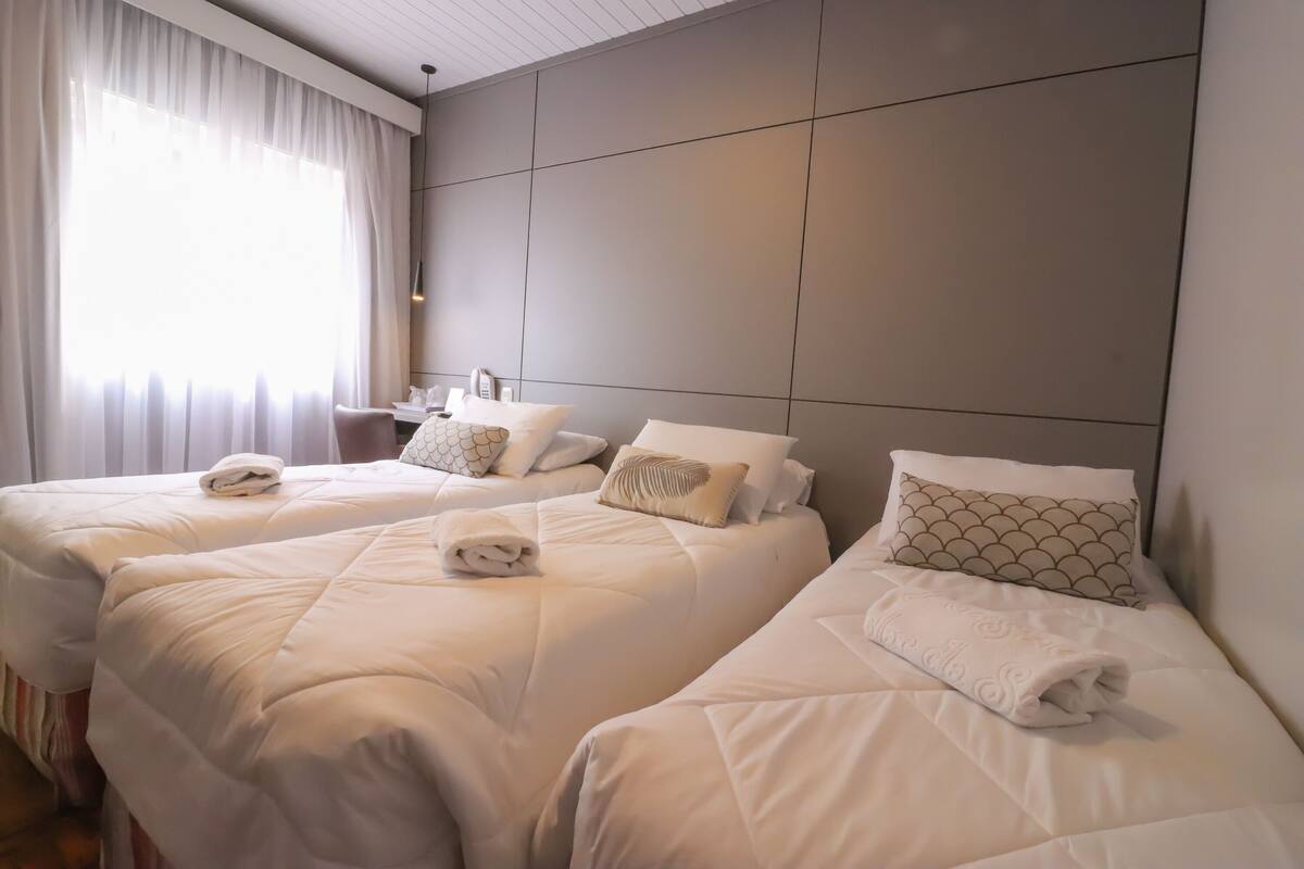 Une chambre d’hôtel avec deux lits, chacun agrémenté de draps blancs et d’oreillers décoratifs.