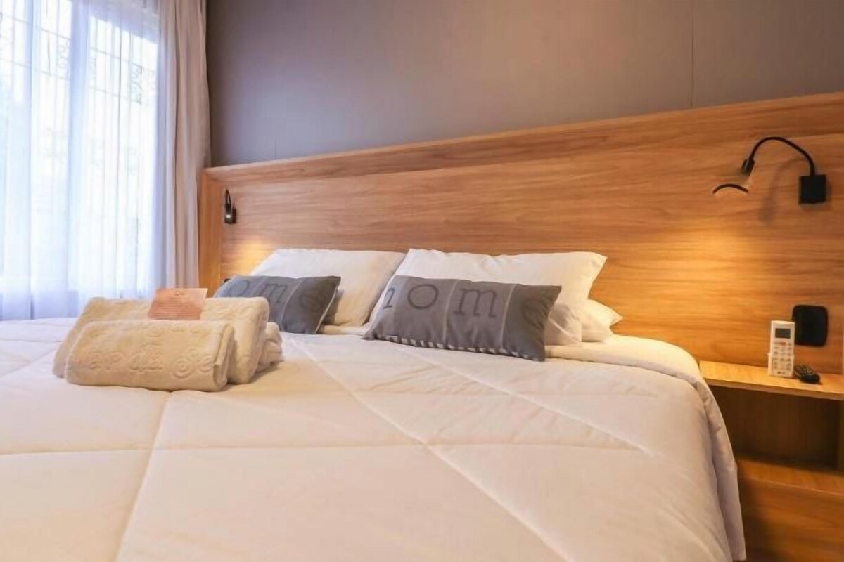 Una habitación de hotel con una cama grande, una mesita de noche y un buró.