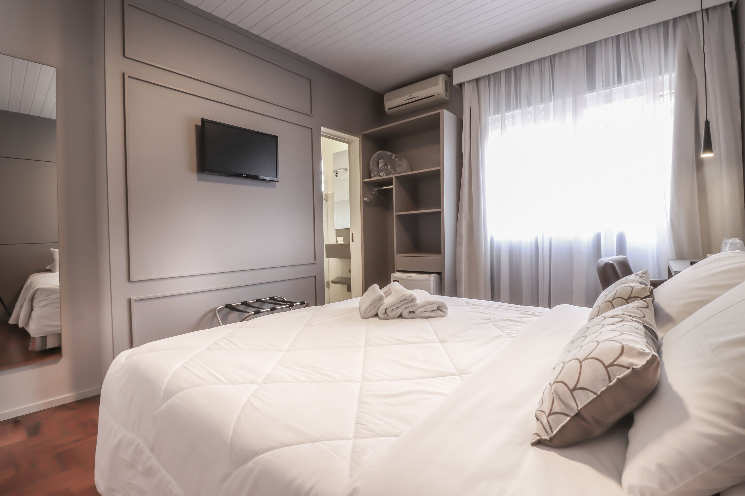 Ett modernt hotellrum med en stor säng, en platt-TV som är monterad på väggen och en rymlig klädkammare.