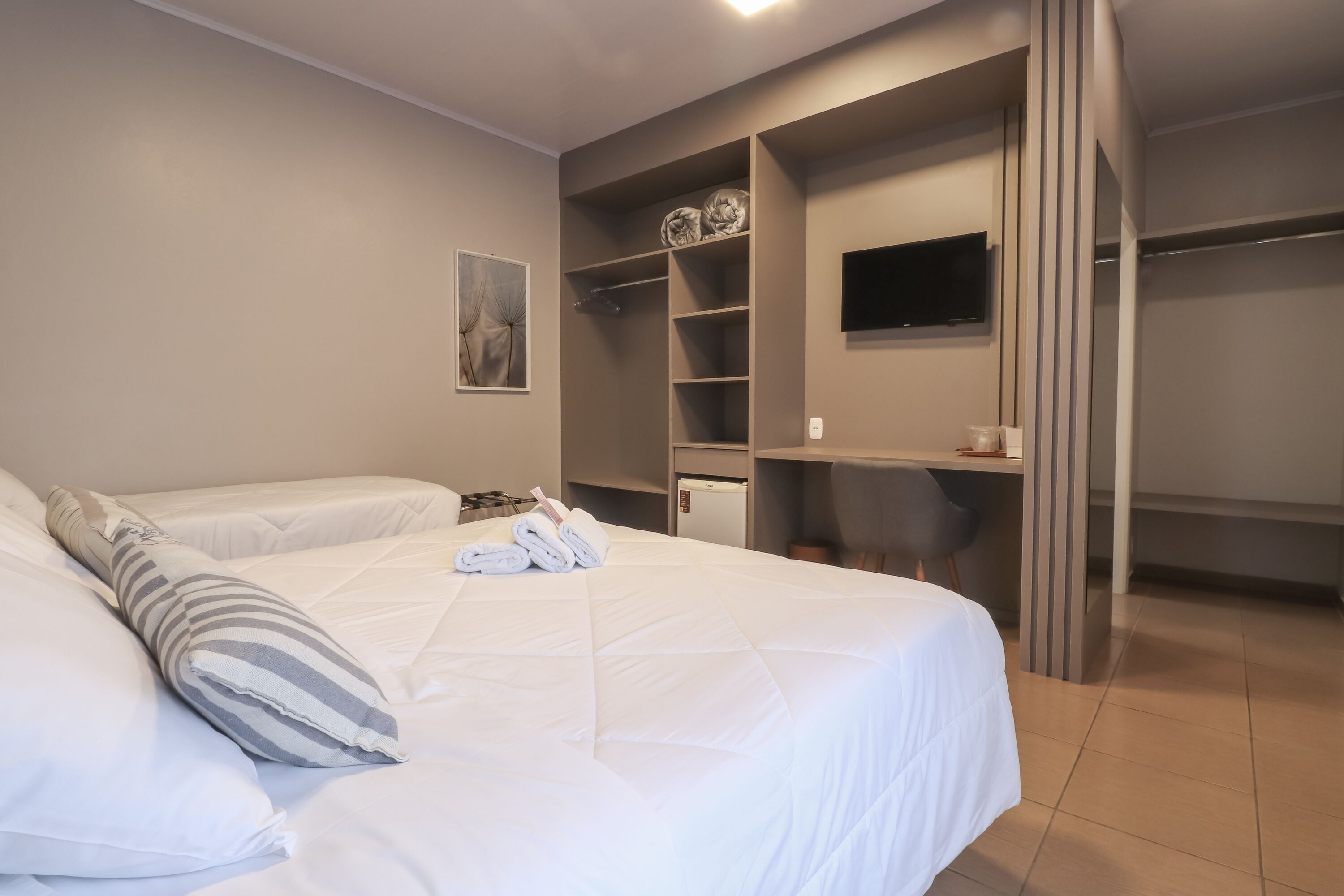 Een hotelkamer met een groot bed, een bureau, een televisie en een kledingkast.