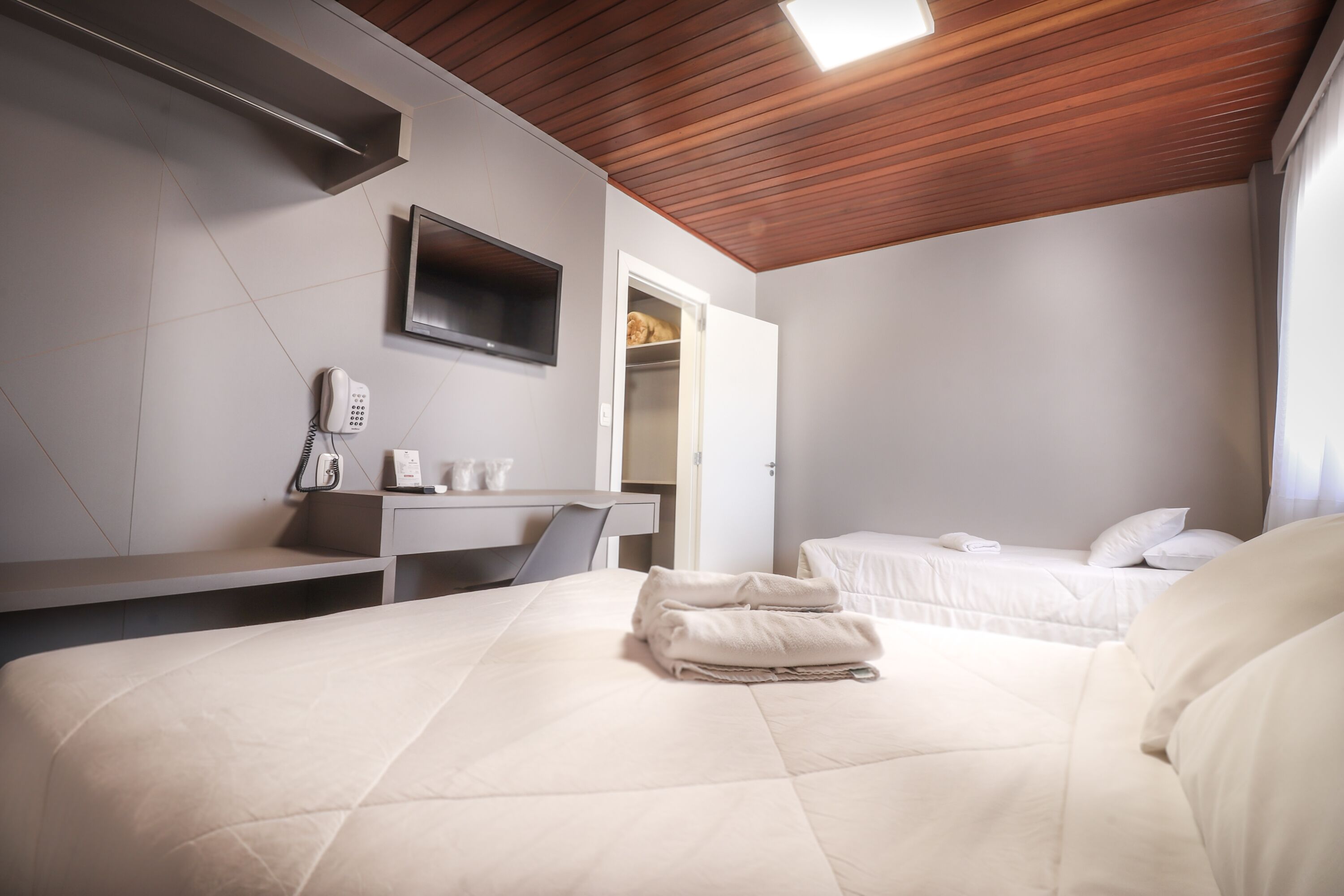 A hotel room with a bed, a desk, a phone, and a closet.