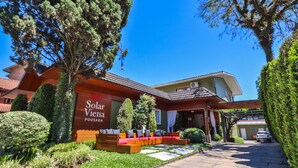 A hotel with a sign reading "Solar Vienna Pousada," a patio with seating, and a well-maintained garden. - Pousada Solar Viena (Gramado)