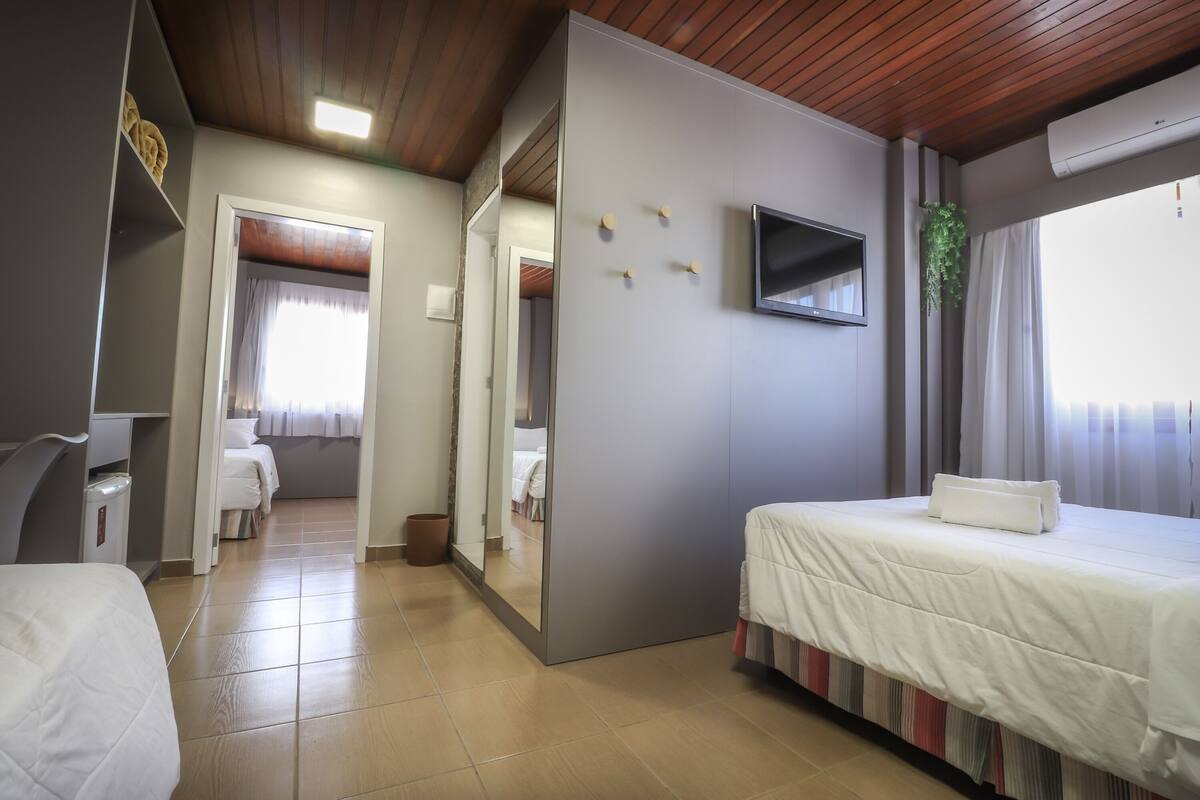 Une chambre d’hôtel avec un lit, un bureau, une chaise, une télévision et un miroir.