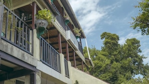 A building with a balcony, potted plants, and a clear sky.