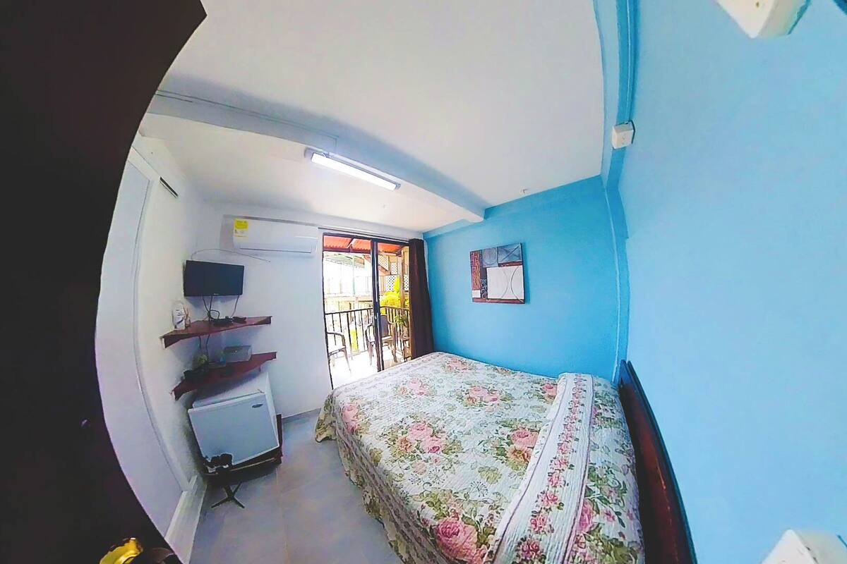 Un dormitorio con cama, televisión, escritorio y ventana.