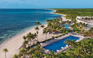Un resort con una amplia piscina, playa y palmeras.