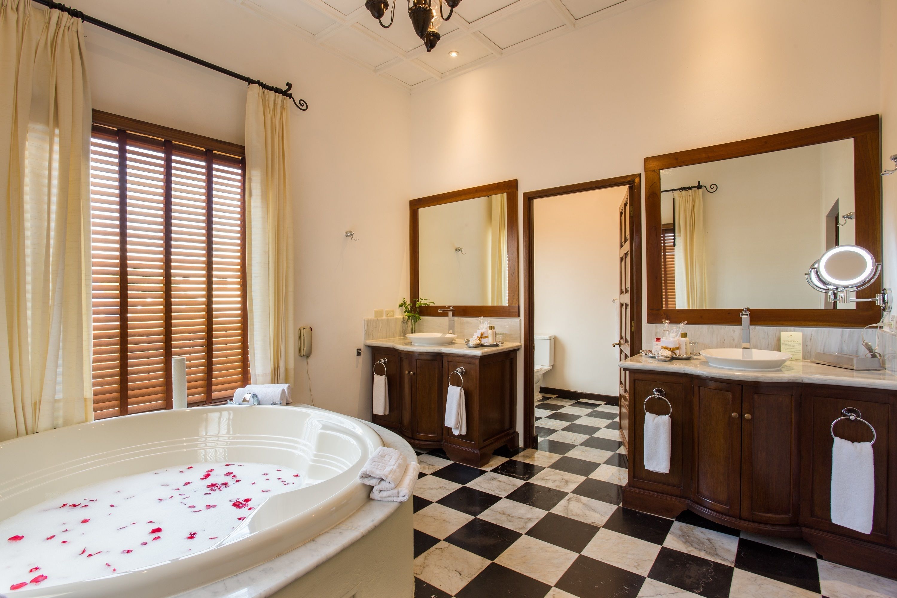 Bathroom with a bathtub, two vanity sinks and a black-and-white tiled floor at Dreams Tulum Resort & Spa