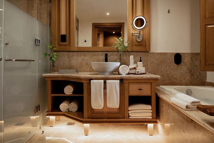 Un bany modern amb una cabina de dutxa de vidre, un moble de bany de fusta amb un rentapeus i una banyera.