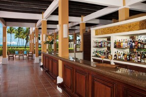 A bar area with a wooden counter and shelves of liquor bottles.