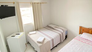 Una habitación pequeña y limpia con cama, escritorio y refrigerador.