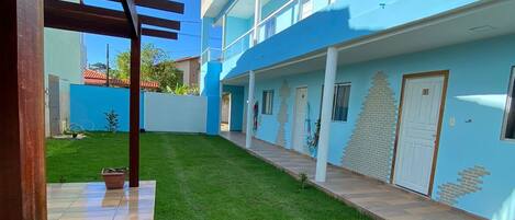 Un edificio moderno con fachada azul, un patio cubierto y un césped bien cuidado.