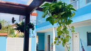 Un espacio al aire libre cubierto con una pérgola, plantas colgantes y una hamaca.