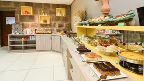 A buffet area with various food items, a coffee station, and decorative shelves. - Pousada Três Pinheiros (Gramado)