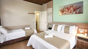 A hotel room with two beds, a wooden ceiling, a painting on the wall, and a bedside table with a lamp. - Pousada Três Pinheiros (Gramado)