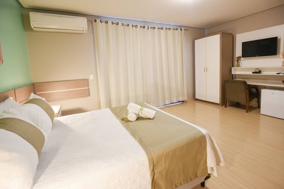 A hotel room with a bed, a desk, a television, and a wardrobe.