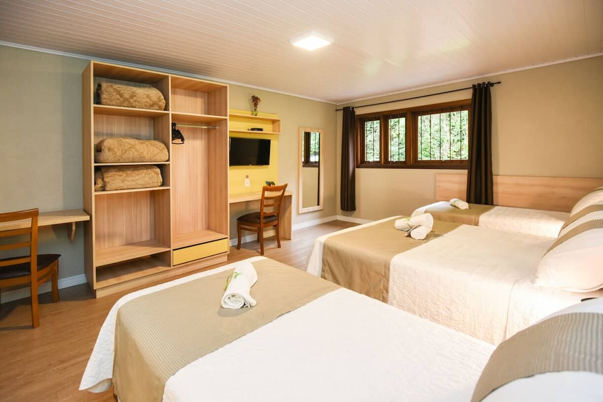 A hotel room with two beds, a desk, a chair, and a wardrobe.
