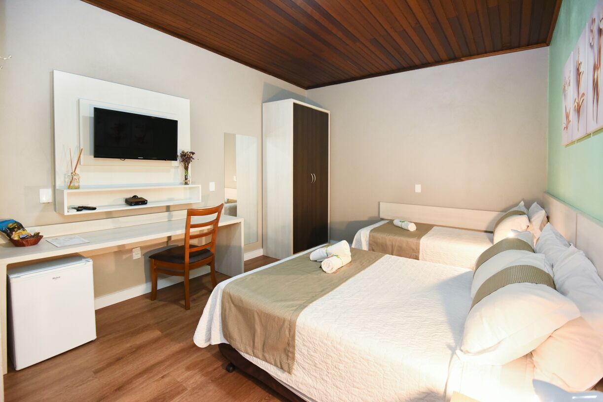 Una habitación de hotel con una cama, un escritorio, una silla, un armario y un televisor.