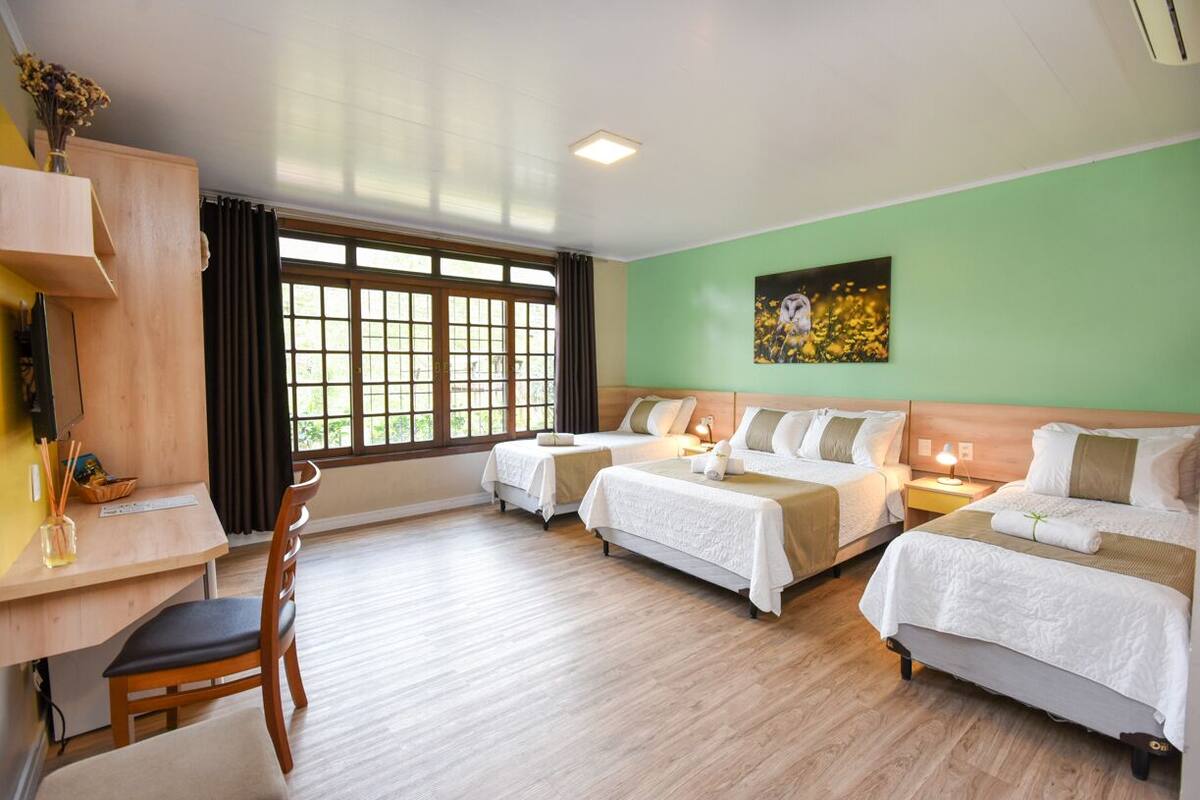 A hotel room with two beds, a desk, and a chair.
