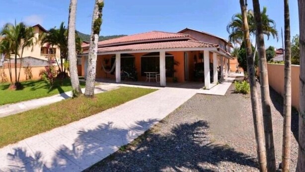 A two-story building with a red-tiled roof and a covered patio area. - Pousada Parque Praia (Penha)