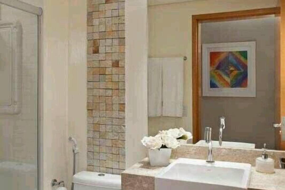 A modern bathroom with a glass shower, a toilet, a sink with a mirror, and a tiled backsplash.