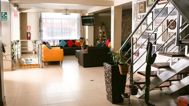 A hotel lobby with a staircase, seating area, and a large plant. - Hotel Mica (Abancay)