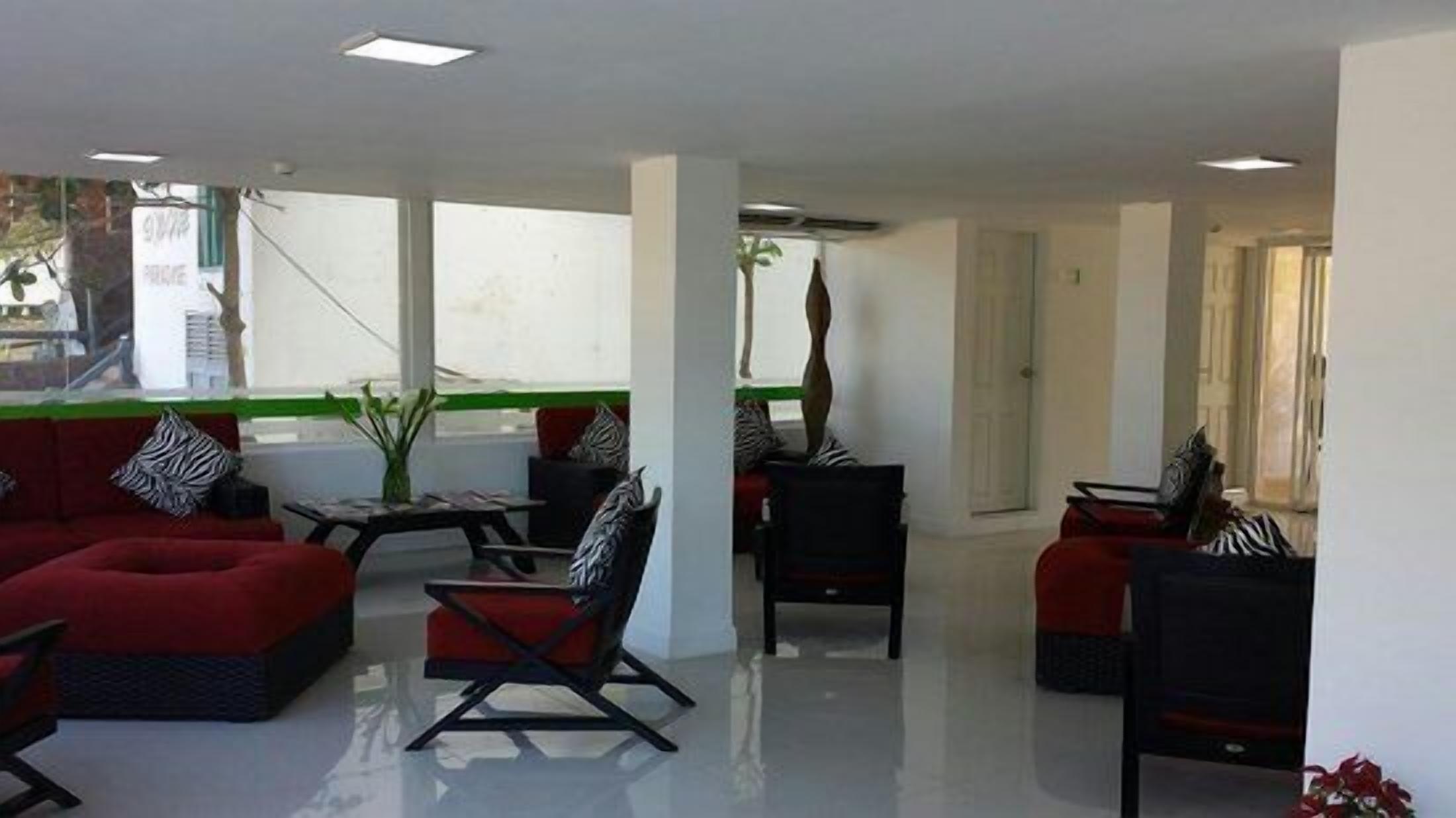 A spacious lounge area with red sofas, black chairs, and a small table.