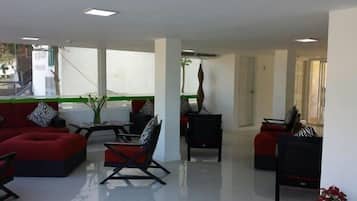 A spacious lounge area with red sofas, black chairs, and a small table.