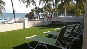An outdoor pool area with artificial grass, lounge chairs, and a view of the ocean. - Yaque Beach Hotel (Díaz)
