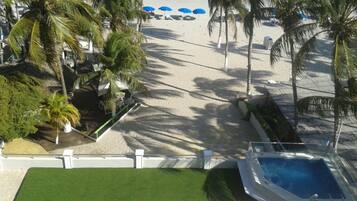 Une vue sur la plage, avec des palmiers, une piscine et des parasols.