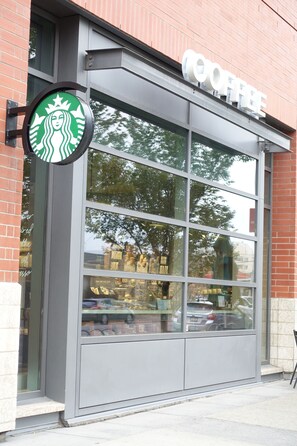 A Starbucks store with a large glass window and a sign above the entrance. - Monki-Di Executive Suites - Alura (Calgary)
