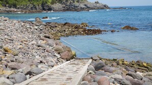 Un camino costero pedregoso que conduce al mar, con una escalera de piedra.