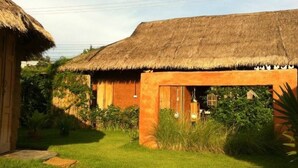 Una casa rústica con techo de paja y un pequeño jardín.