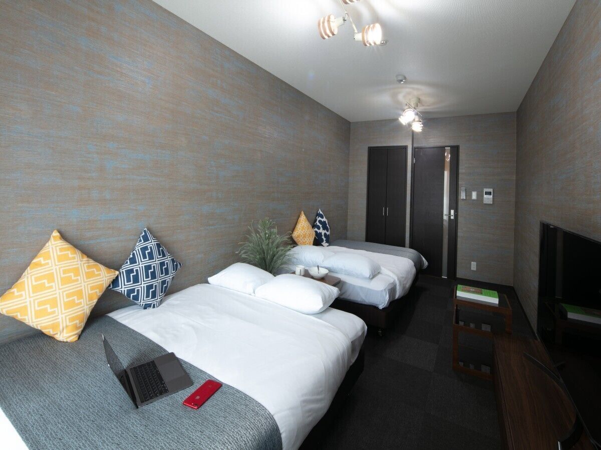 Hotellihuone, jossa on kaksi sänkyä, televisio, työpöytä ja takka.