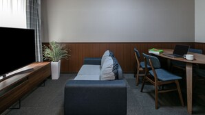 Un salon moderne avec un téléviseur à écran plat, un canapé, une table à manger avec des chaises et une plante en pot.