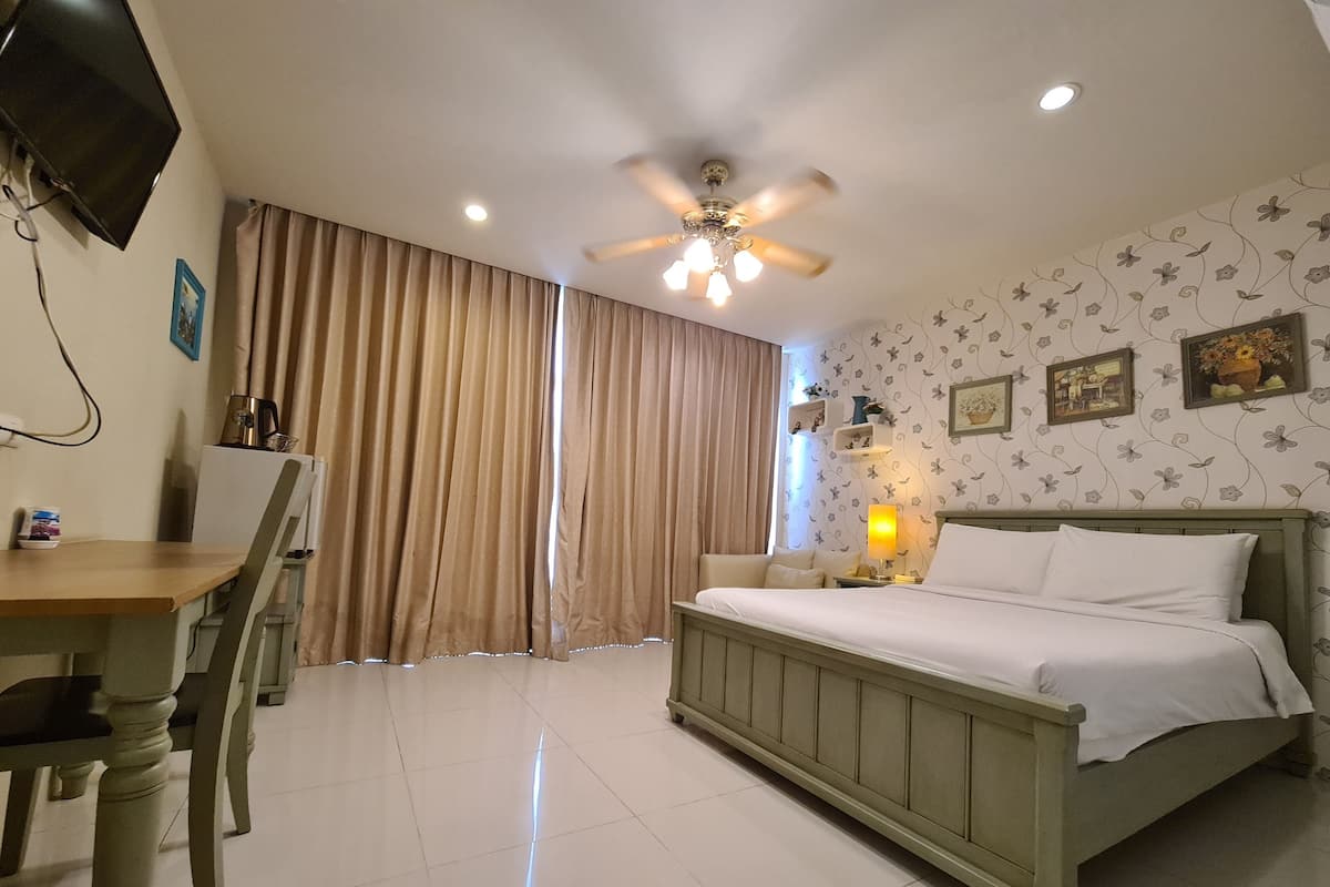 Une chambre d’hôtel équipée d’un lit, d’un bureau, d’une chaise, d’un ventilateur de plafond et d’un téléviseur.
